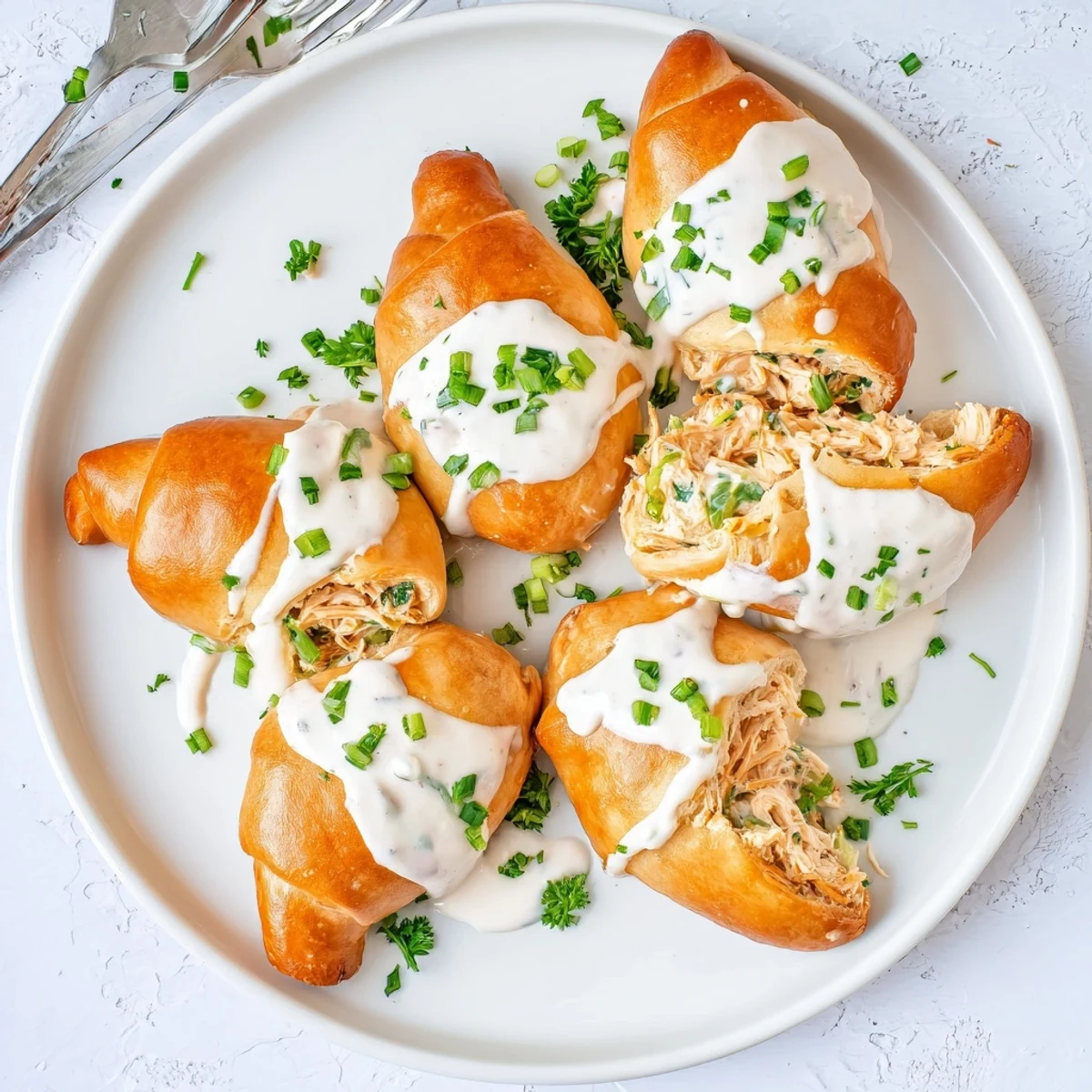 Flaky chicken pillows stuffed with seasoned chicken breast and served with homemade cheesy sauce