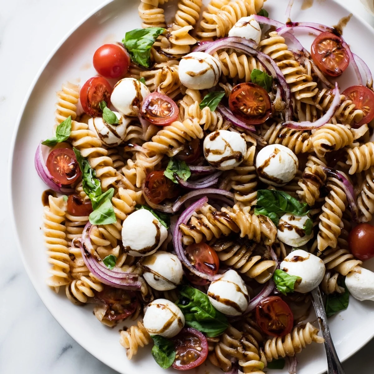 Colorful Caprese Pasta Salad with ripe tomatoes, creamy mozzarella, and fresh basil leaves